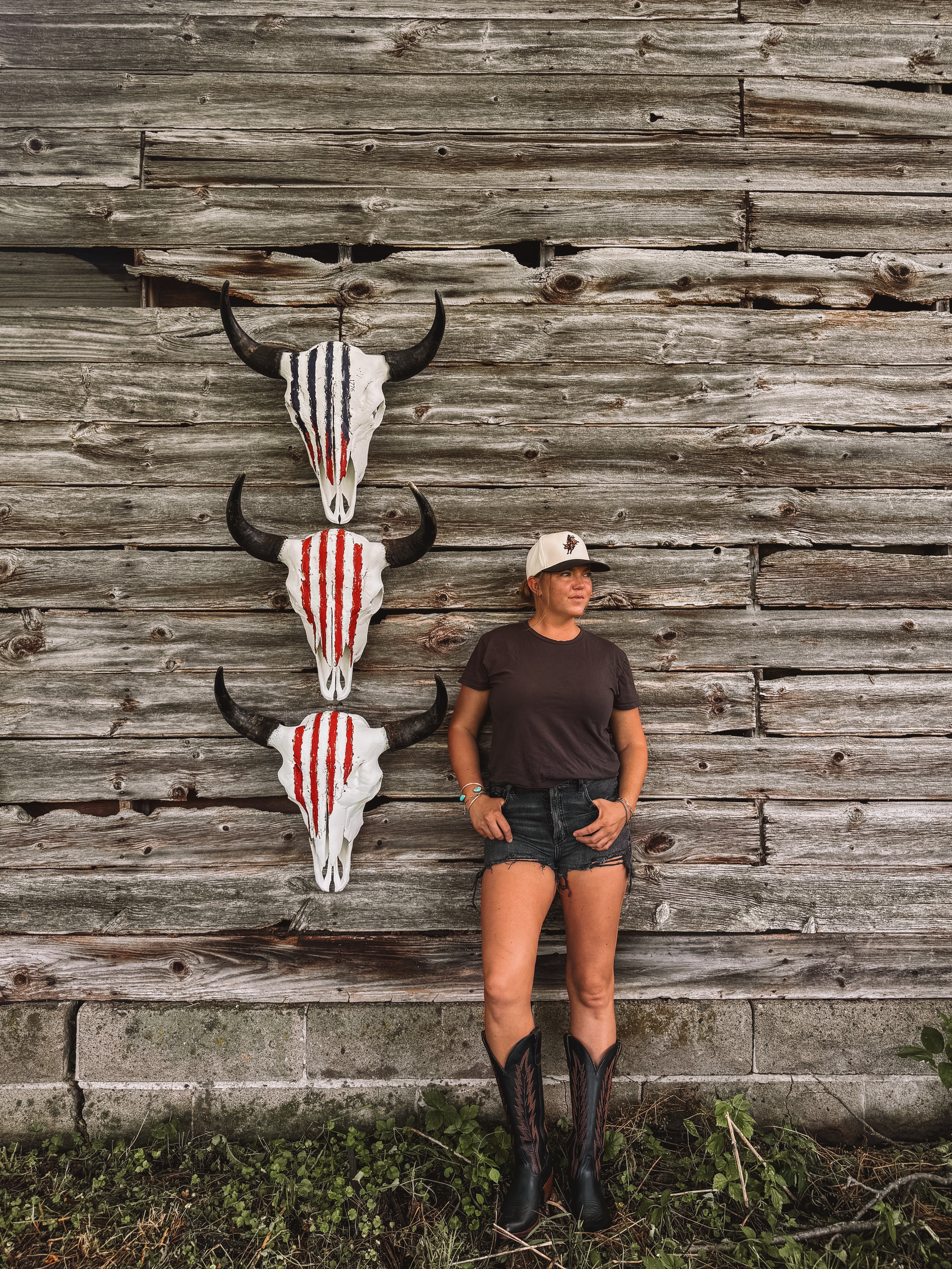 Wanderlust Skulls owner standing in front of wood wall with American 250th Celebration American Buffalo American flag skulls