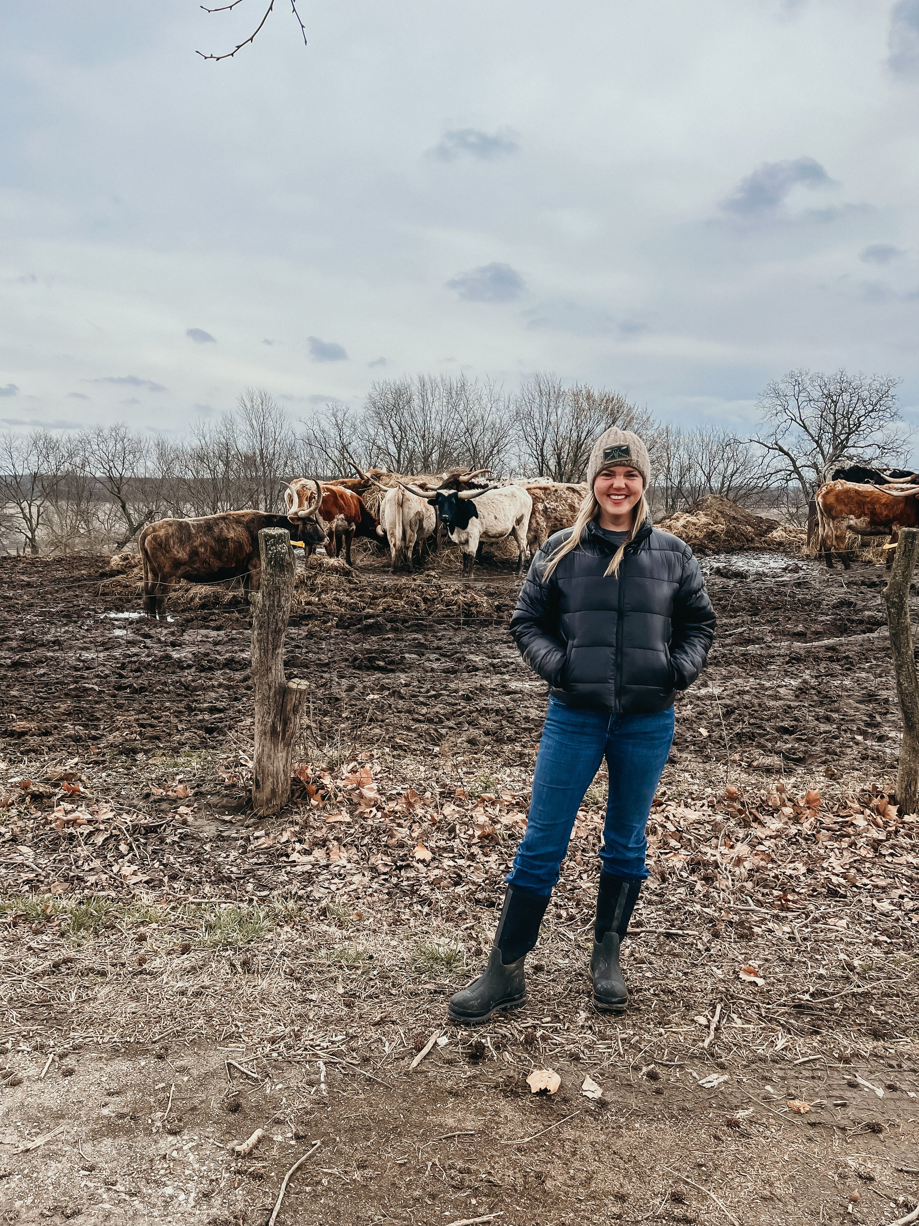 Wanderlust Skulls designer Cassie Everson standing in front of a herd of longhorn cattle in winter