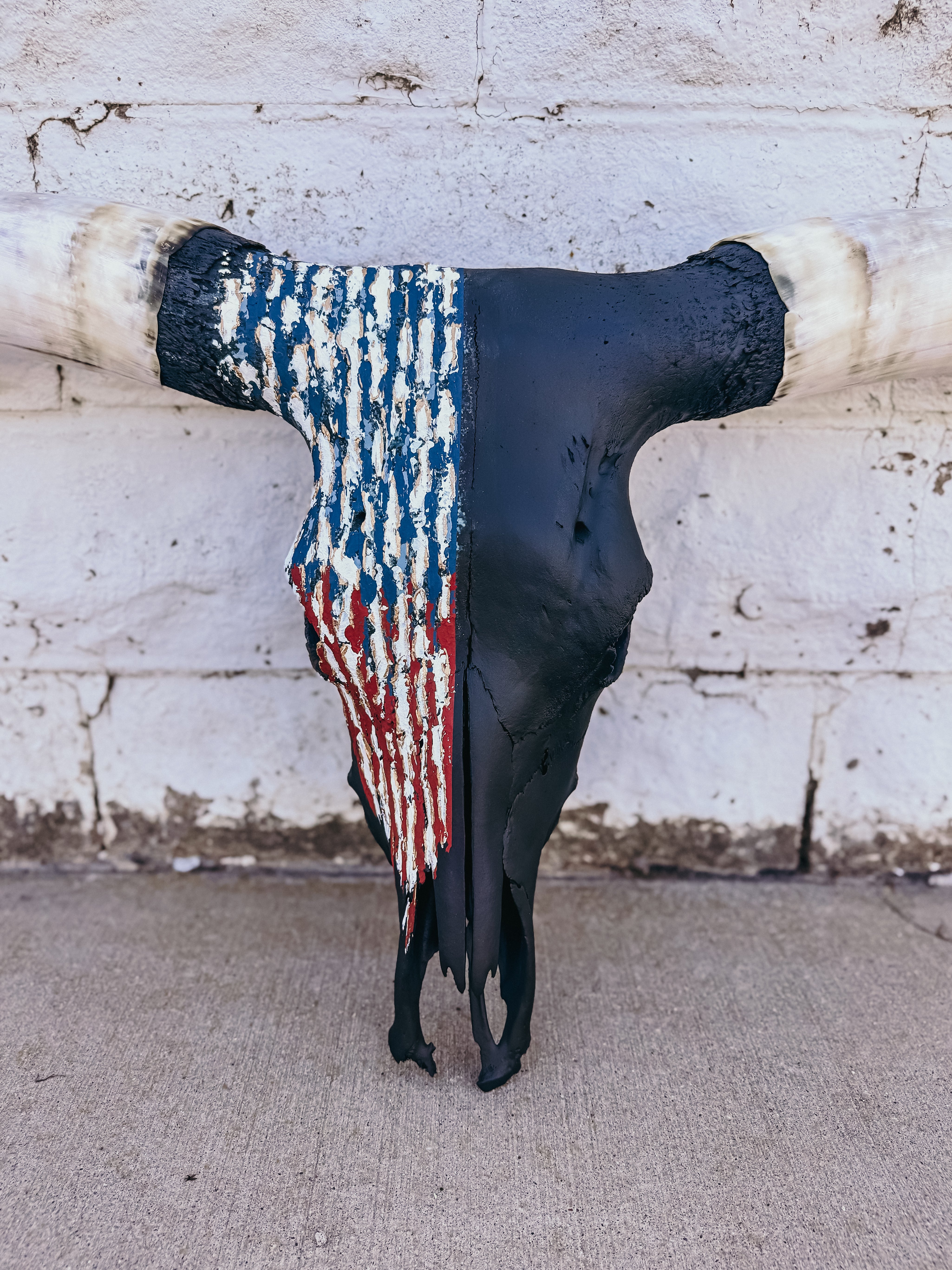 Decorative longhorn skull with American flag pattern on a textured wall background