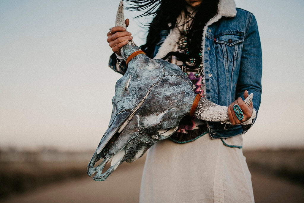 Person holding a handcrafted American buffalo skull with decorative artwork by Wanderlust Skulls