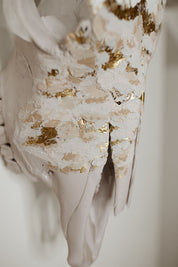 White sculpture with gold leaf detailing on a neutral background