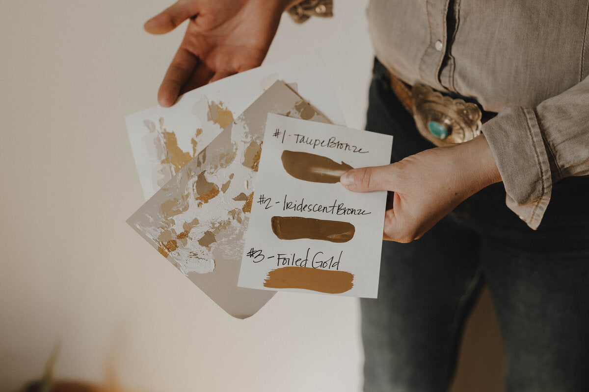 Person holding color swatch cards with gold and bronze tones for custom created  longhorn cow or american buffalo skull